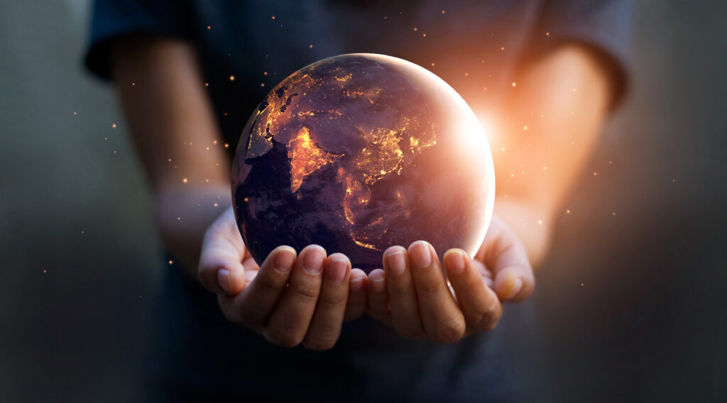 Un globe terrestre illuminé vu de nuit, tenu dans les mains d’une personne, symbolisant la protection et la responsabilité environnementale.