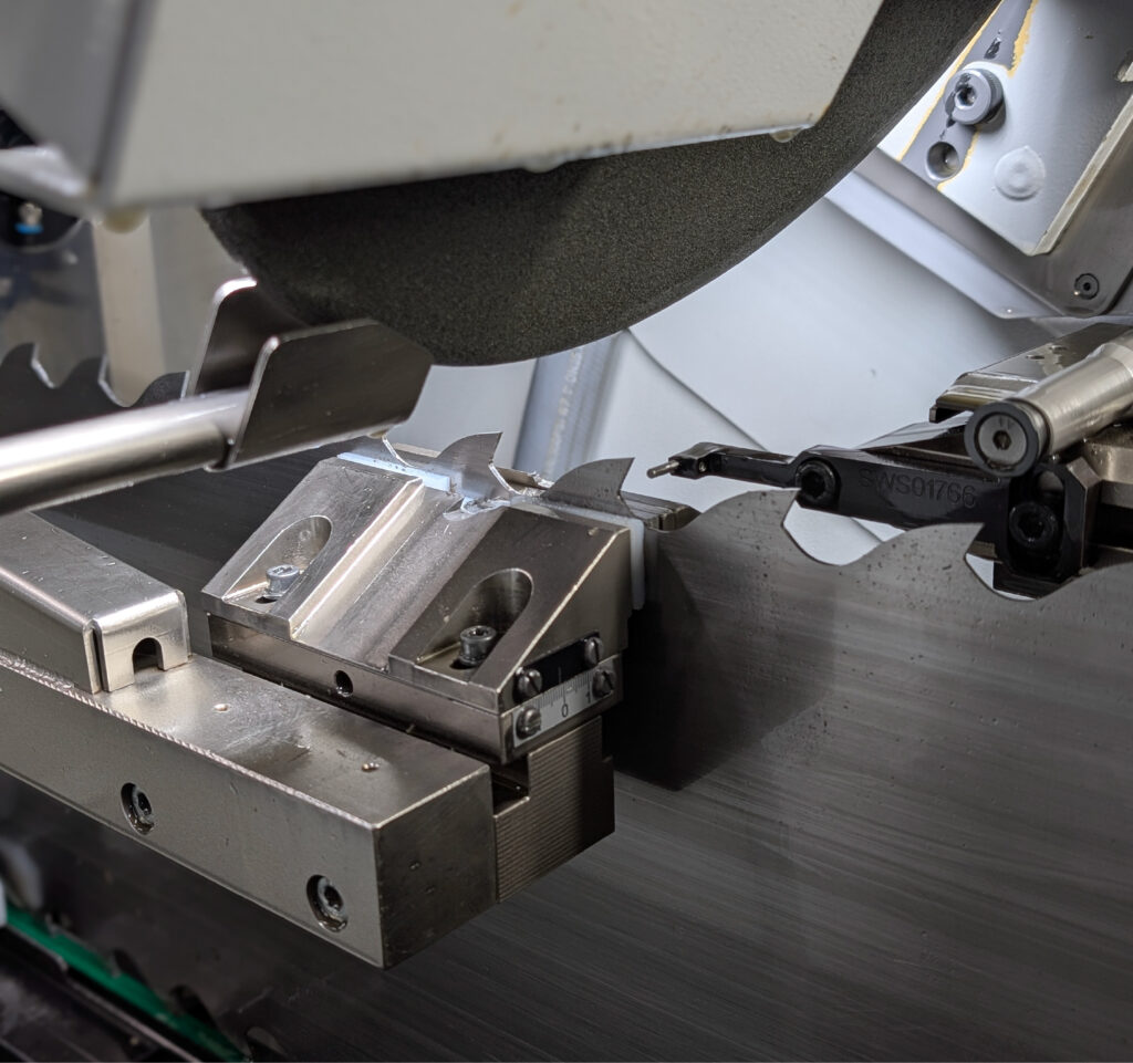 The process of sharpening a band saw blade with an abrasive wheel in a specialist workshop.