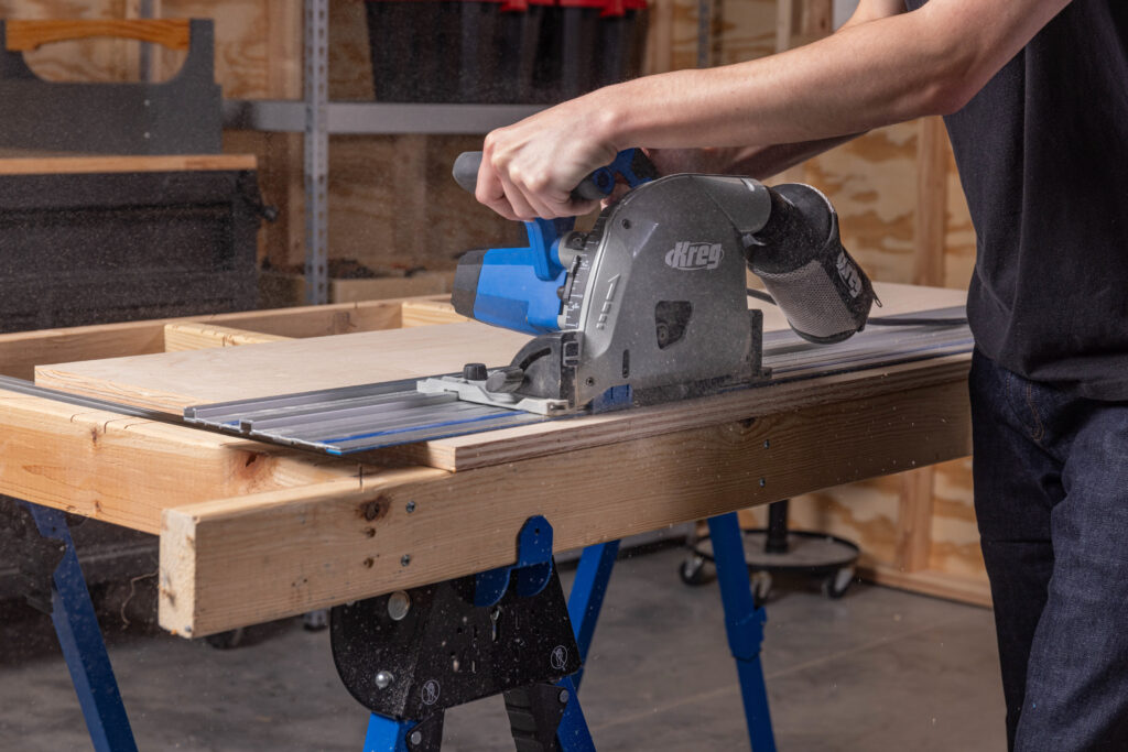 Woodworking with a Kreg ACS2100 plunge saw guided on a rail, enabling a straight cut to be made on a plank of wood.