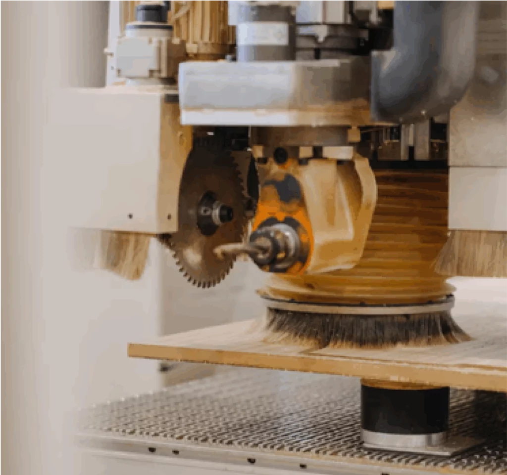 CNC machine machining a wooden panel with a rotating head fitted with milling cutters and circular blades.