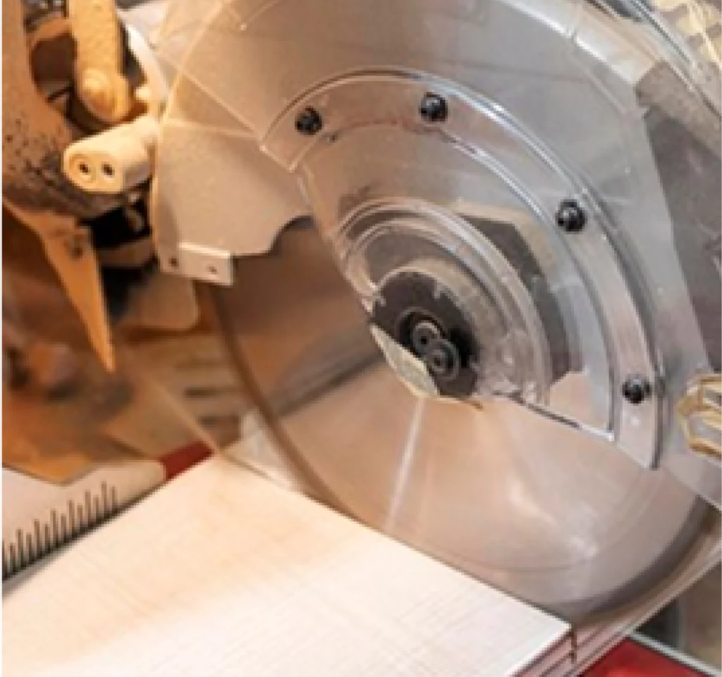 Electric mitre saw making a clean cut on a piece of wood in a joinery workshop.