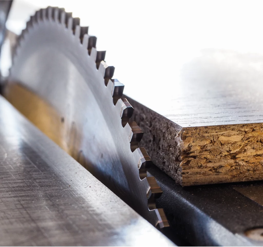 Circular saw blade cutting particle board in a joinery workshop.