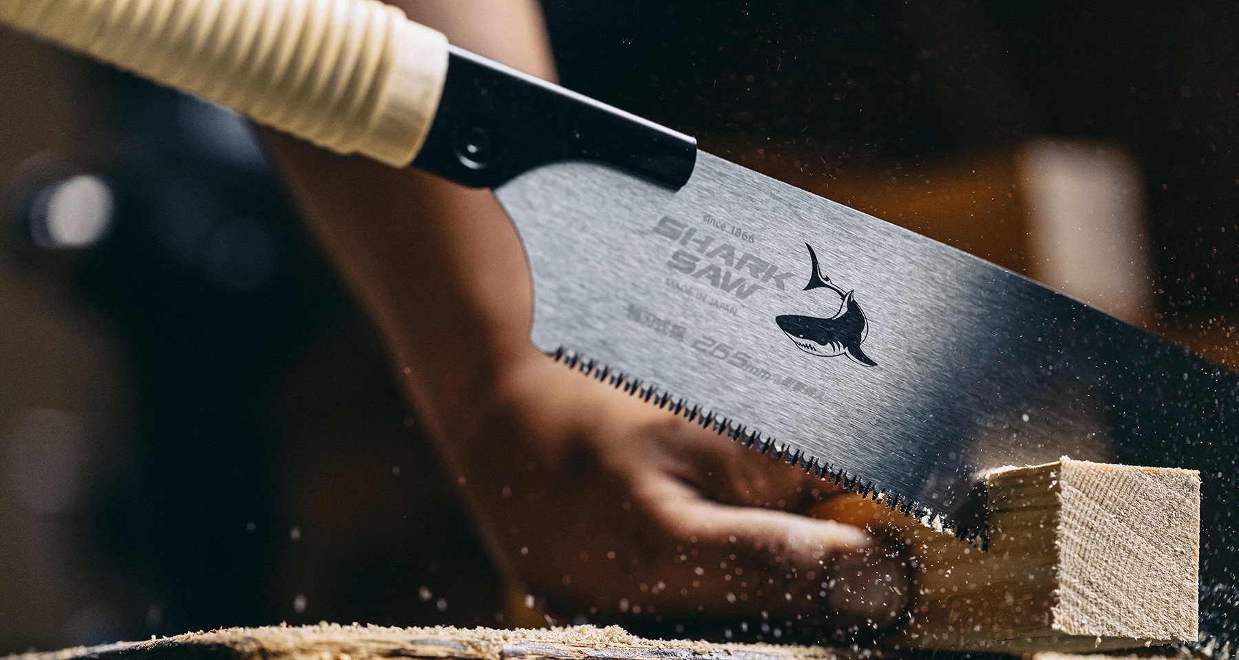 Japanese Kataba Shark Saw cutting a piece of wood, with visible sawdust projection.