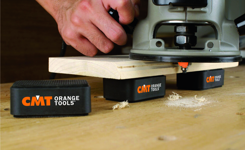 Woodworking with a router, the workpiece is held in place by CMT Orange Tools holding blocks.
